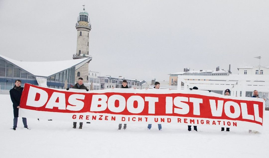 Mitglieder der Jungen Alternative mit einem Das-Boot-ist-voll-Banner in Warnemünde